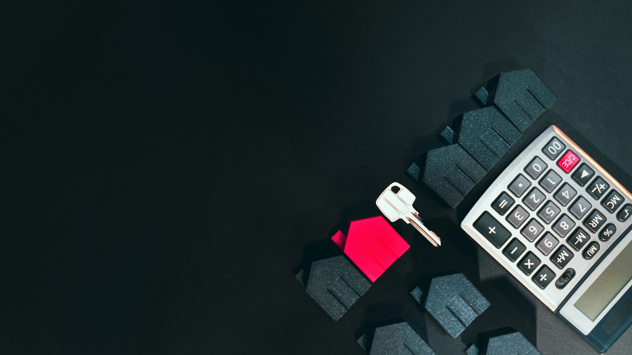Calculator with a house key and icons of houses, with one red house icon standing out among black house icons on a dark background.