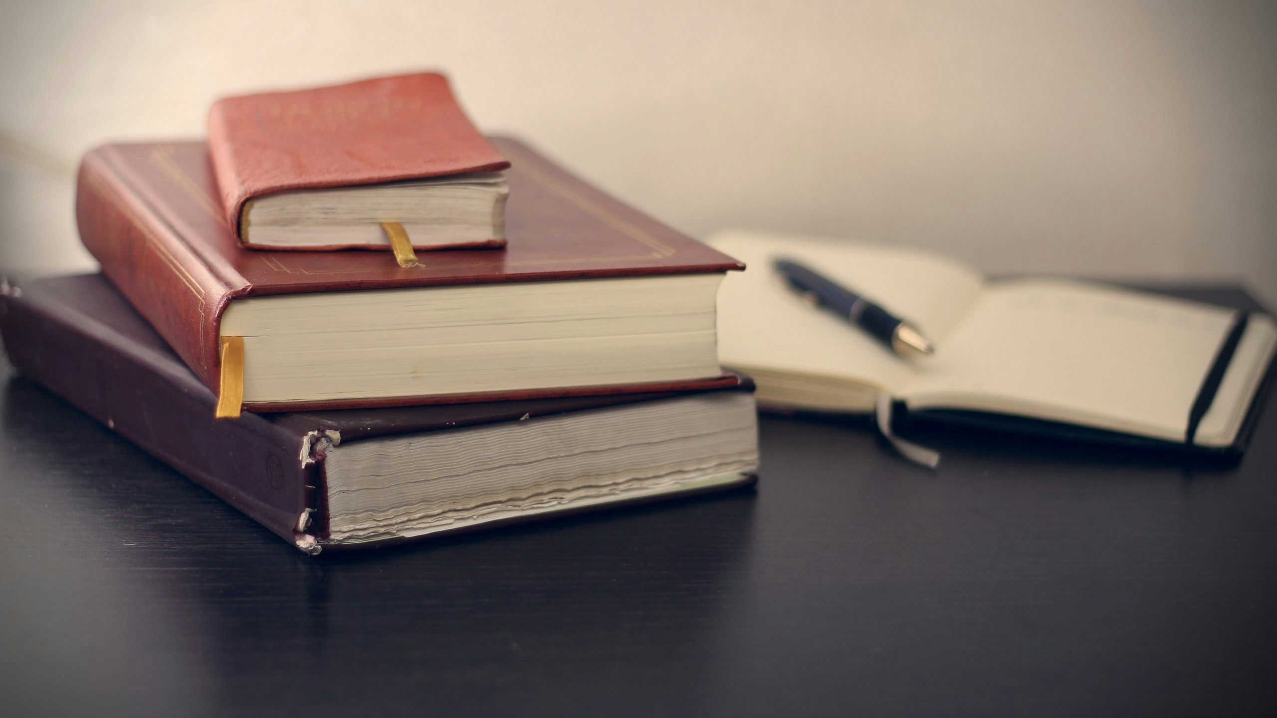 Desk with three closed notebooks, an open notebook, and a pen placed on the open pages, symbolizing organized legal documentation.